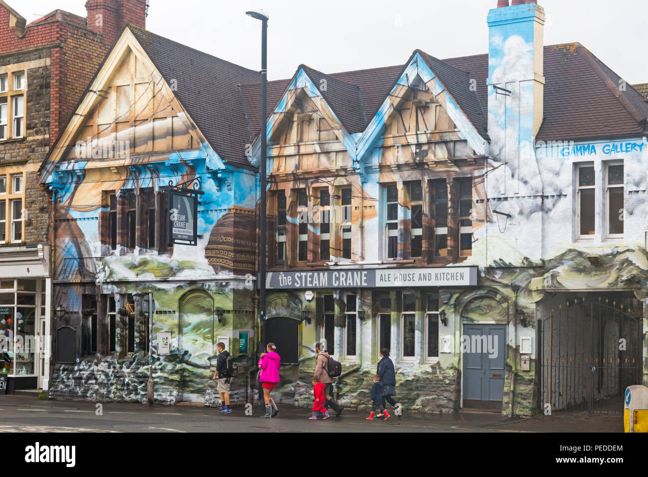 Visiteurs en passant devant la grue à vapeur ale house et cuisine avec l'art de rue sur North Street, Bristol sur un jour de pluie en août Banque D'Images