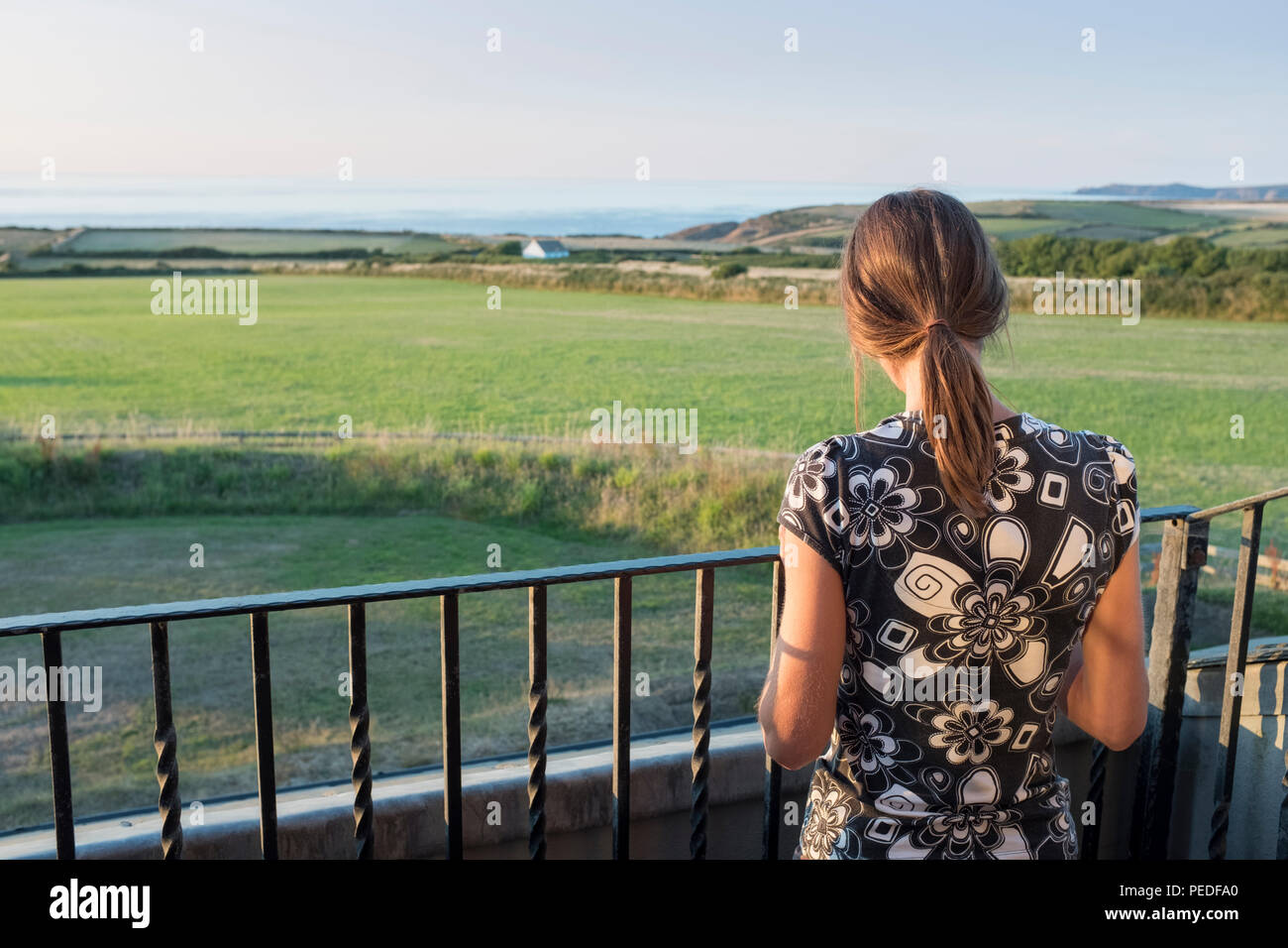 Une jeune femme debout sur un balcon face à la mer. Banque D'Images
