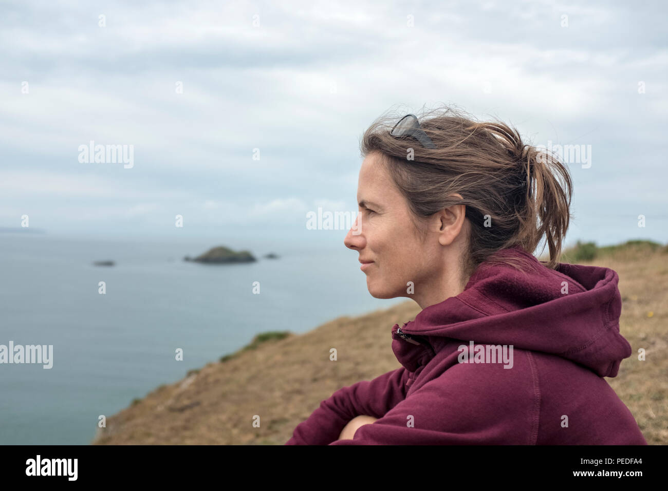 Une jeune femme assise, face à la mer. Banque D'Images