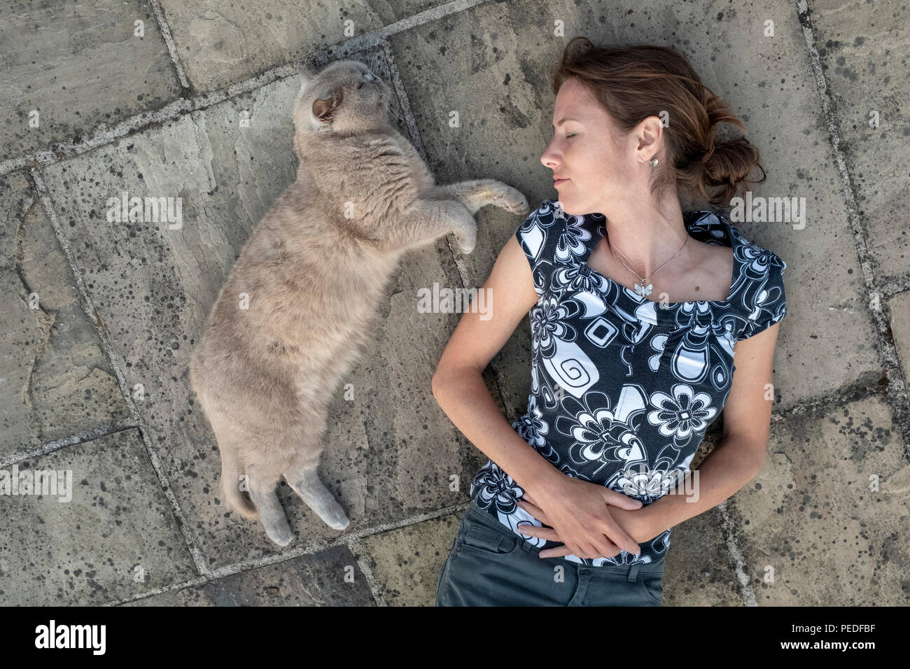 Une femme et son chat couché ensemble sur le terrain. Banque D'Images