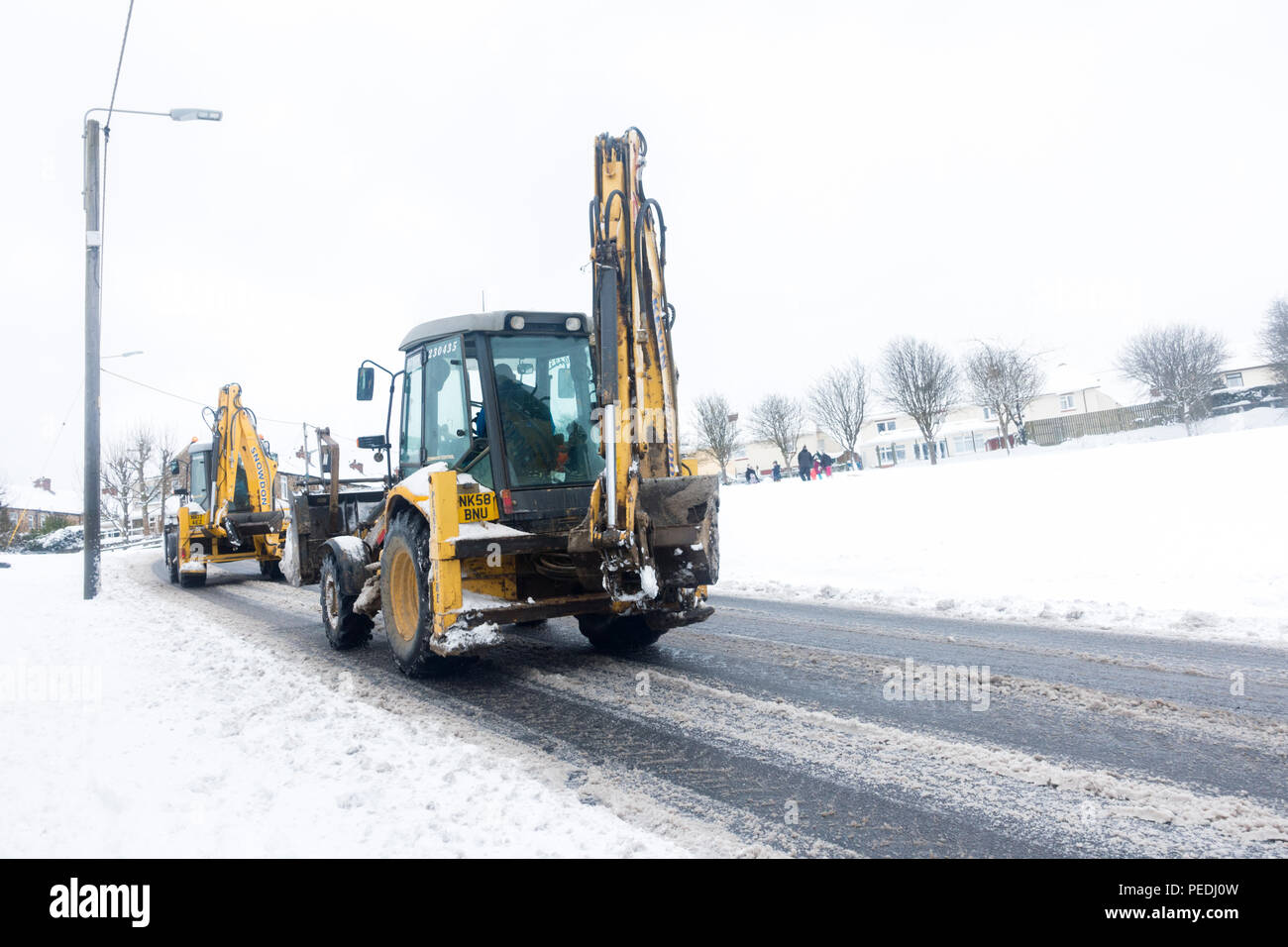 Deux pelleteuses roulant le long d'une route urbaine couvertes de neige en Consett, County Durham, Royaume-Uni, Banque D'Images