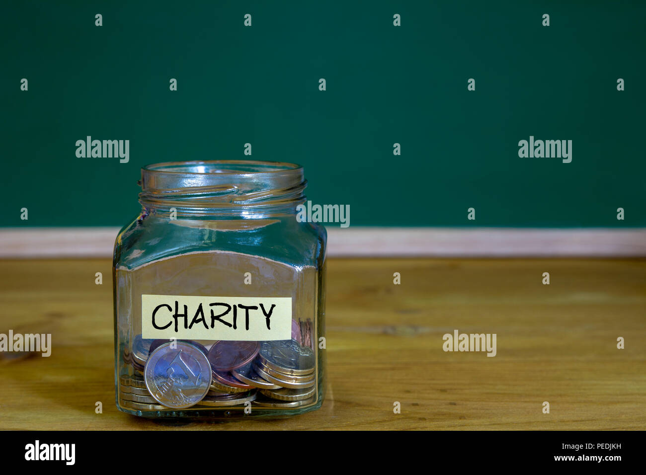 Pièces dans le bol ou le verre sur le bureau en bois avec étiquette de bienfaisance contre green chalkboard arrière-plan. Banque D'Images