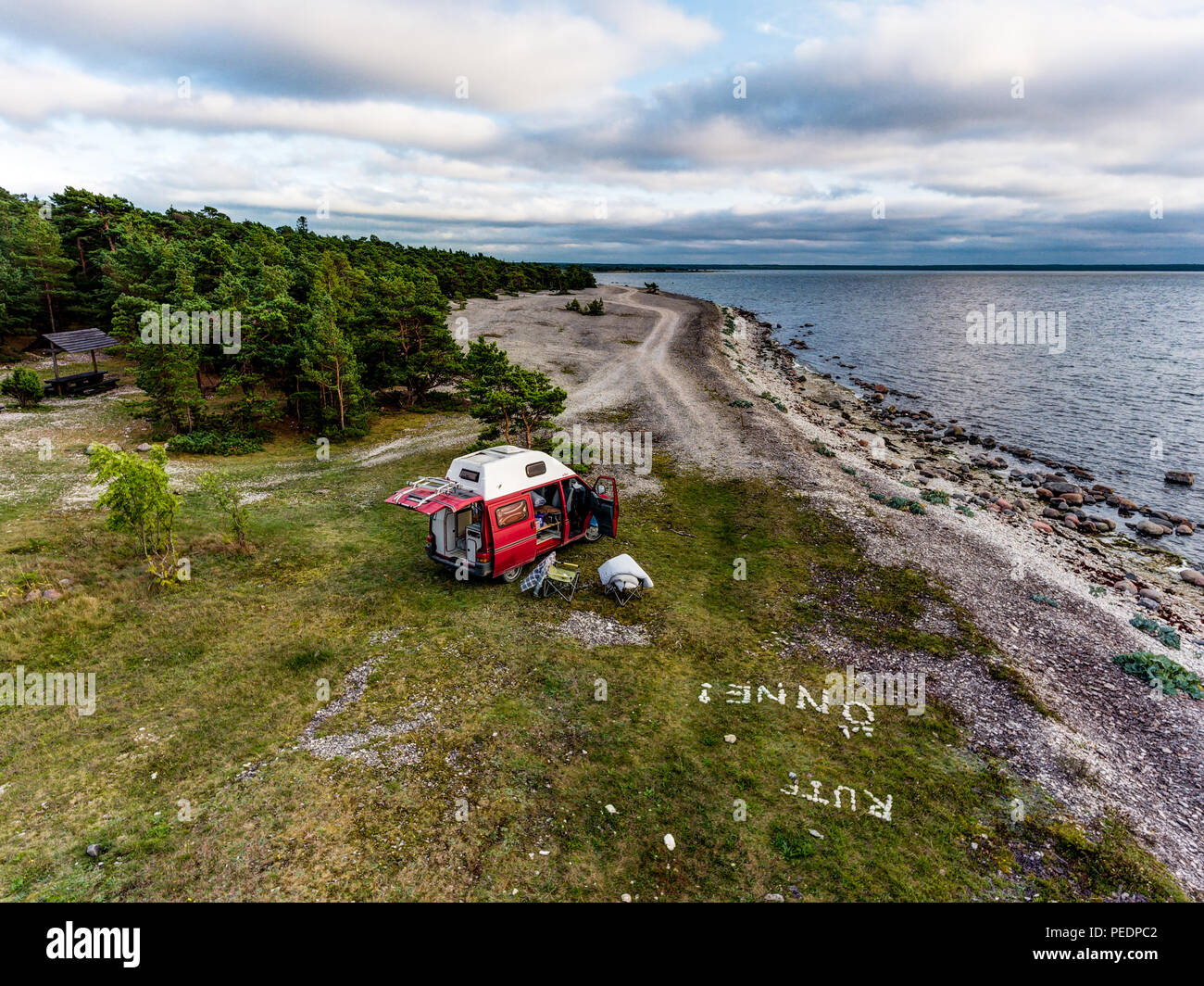 Estonie - Août 2018 : VW Transporter T4 sur mer baltique avec coucher du soleil en arrière-plan et ciel bleu avec des nuages. Au premier plan, l'équipement de camping est situé Banque D'Images