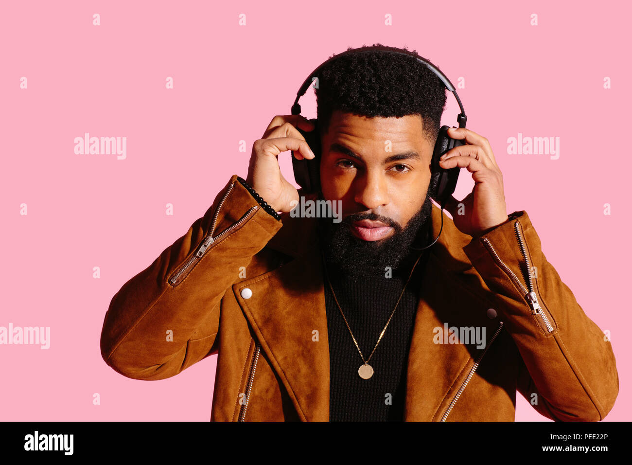 Horizontall portrait d'un homme cool avec barbe et un casque isolé sur fond de studio rose Banque D'Images