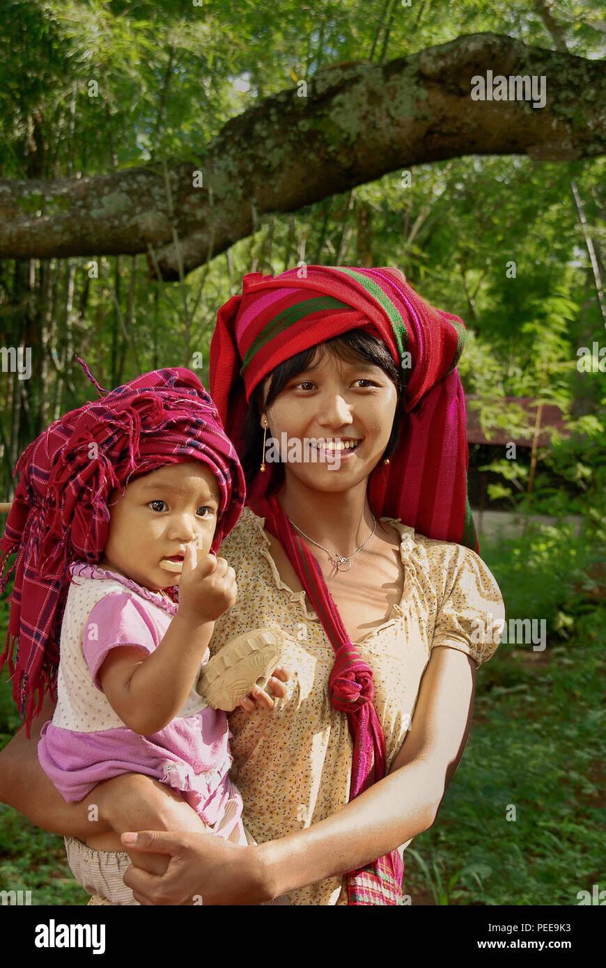 Une jeune femme du village est tenir l'enfant et sourit. Banque D'Images