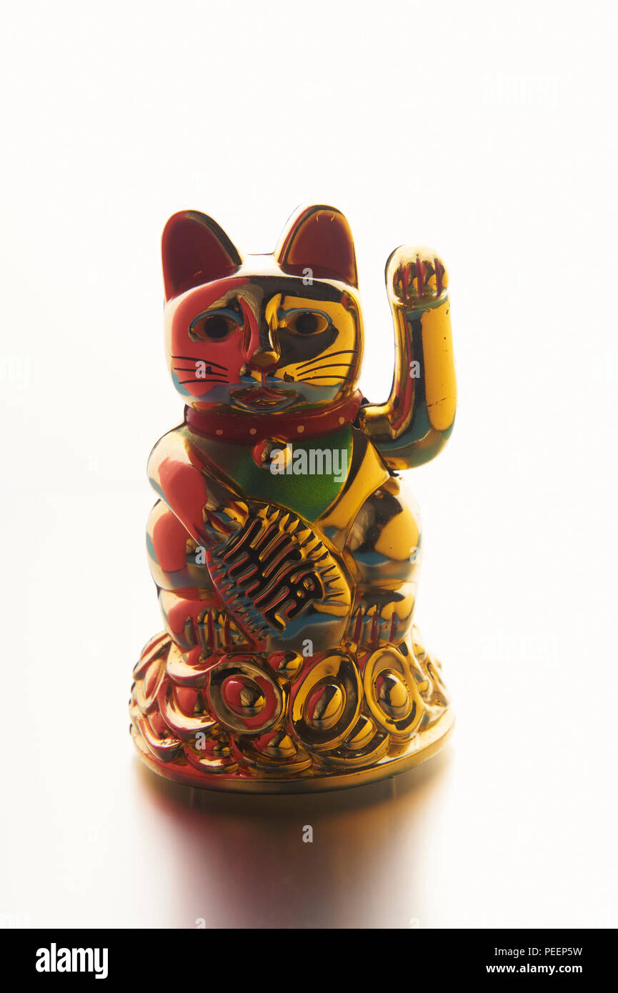 Golden Maneki-neko ou signe de chance chinois chat ou chat, avec patte gauche en position verticale (pour attirer les clients), sur un fond blanc Banque D'Images