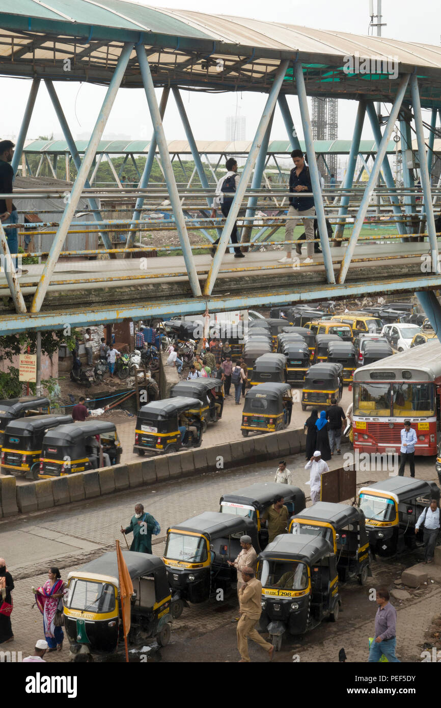Auto rickshaw Tuk Tuks attendent des passagers à la gare de Bandra avec une passerelle pour piétons au-dessus de la Station Road, Mumbai, Inde Banque D'Images