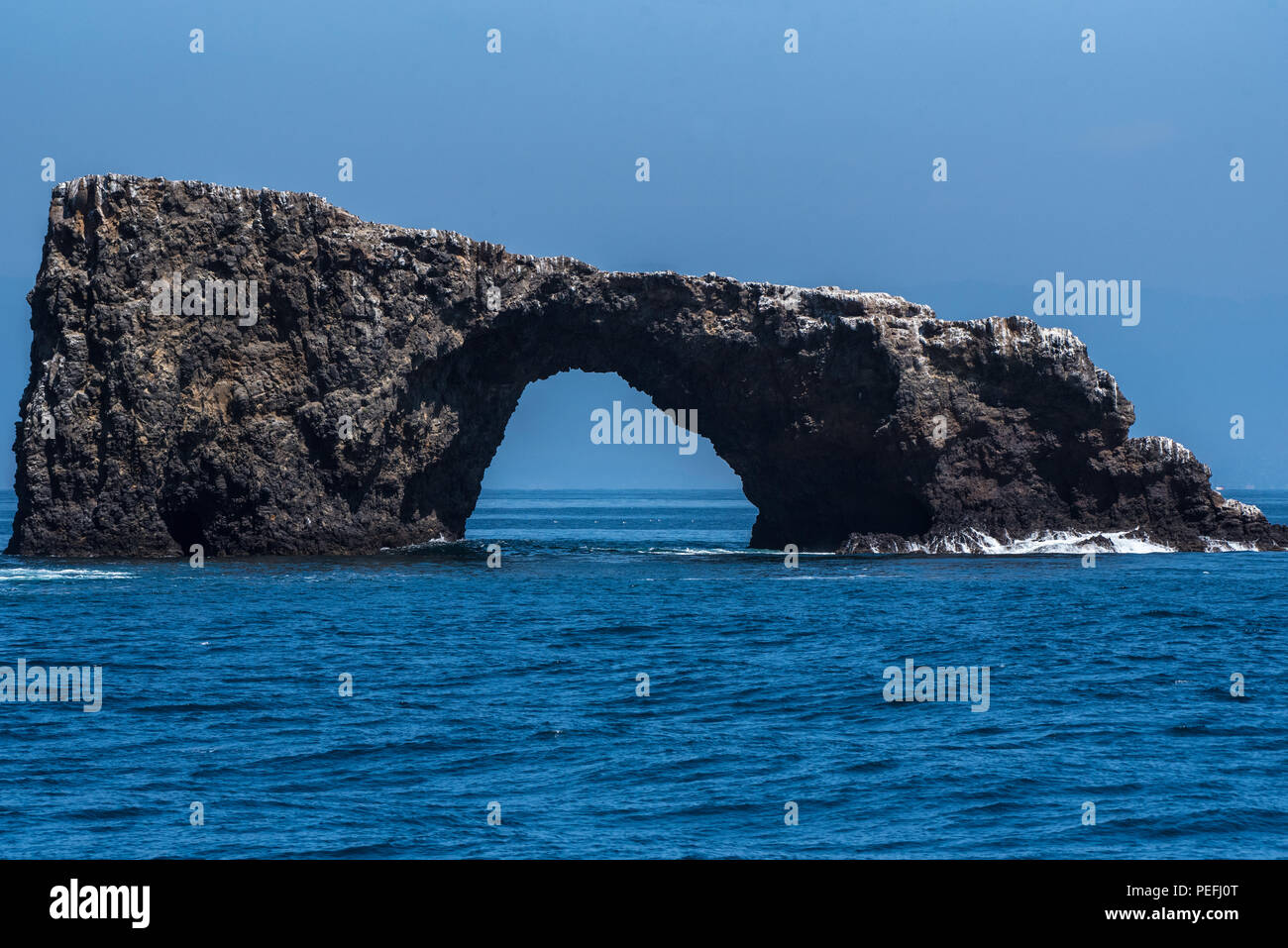 Arch Rock sur la pointe est de l'Île Anacapa avec de petites vagues se briser contre la base sur une journée typique de ciel bleu. Banque D'Images