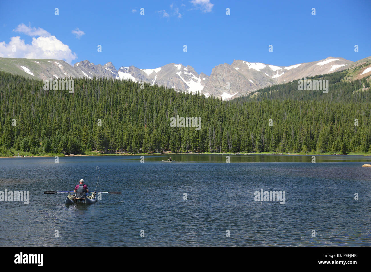 Aviron pêcheur sur un bateau sur le lac de Brainard du Colorado avec les Rocheuses de l'Indian pics dans l'arrière-plan Banque D'Images