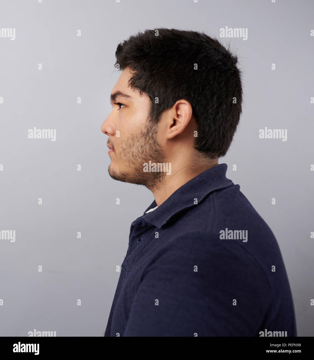 Jeune homme Vue de profil isolé sur fond gris studio Banque D'Images