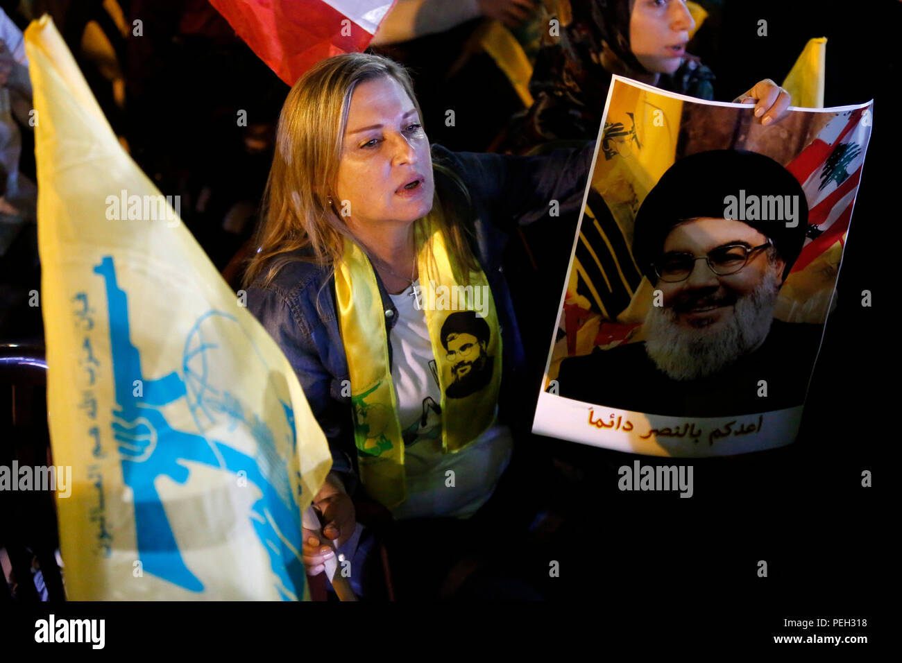 Beyrouth, Liban. Août 14, 2018. Une femme tient le drapeau du Hezbollah et de l'image de leader du Hezbollah Sayyed Hassan Nasrallah lors de Nasrallah livrant un discours télévisé, à Beyrouth, Liban, 14 août 2018. Le chef du Hezbollah Sayyed Hassan Nasrallah a appelé mardi les partis politiques à maintenir leurs efforts de négociation jusqu'à ce qu'ils atteignent un consensus sur la formation du cabinet au Liban. Credit : Bilal Jawich/Xinhua/Alamy Live News Banque D'Images