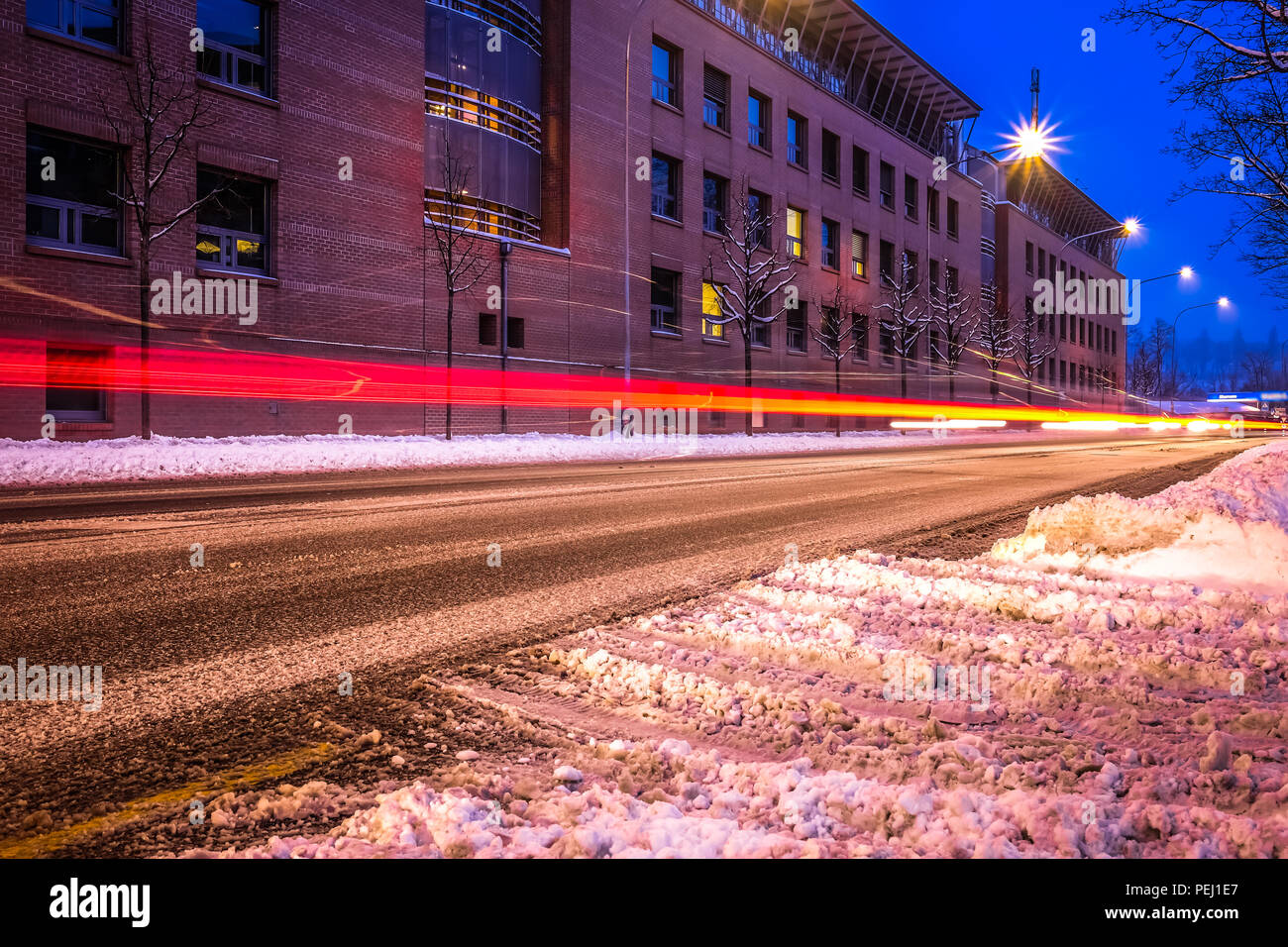 Une longue exposition photo de la rue de Fribourg en Suisse, avec la neige sur la route, véhicule tout en légèreté et une université dans l'arrière-plan Banque D'Images