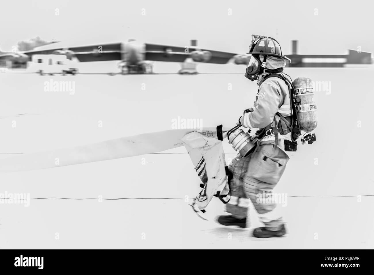 Un pompier du 5e Escadron de génie civile tire un flexible à travers la piste lors d'un exercice d'entraînement à Minot Air Force Base, N.D., le 28 août 2015. Le but de l'exercice était d'inspecter et d'évaluer la capacité du ministère à la réalisation de la mission en toute sécurité et de travailler en équipe. (U.S. Air Force photo/ Navigant de première classe J. T. Armstrong) Banque D'Images