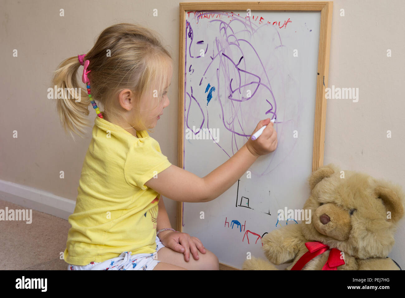 Jeune fillette de deux ans le dessin avec un stylo de couleur sur un tableau blanc, d'être artistique, Banque D'Images