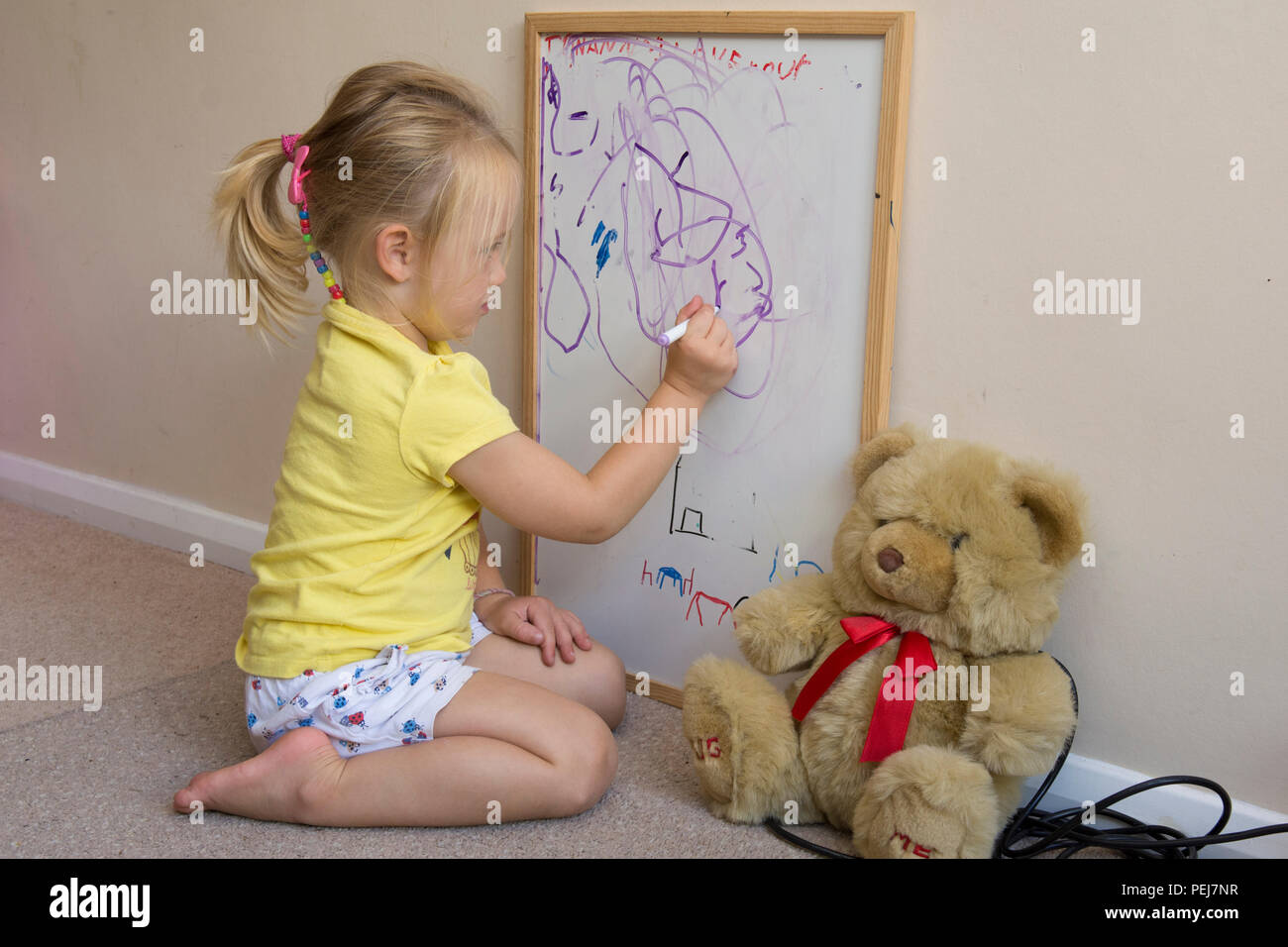 Jeune fillette de deux ans le dessin avec un stylo de couleur sur un tableau blanc, d'être artistique, Banque D'Images