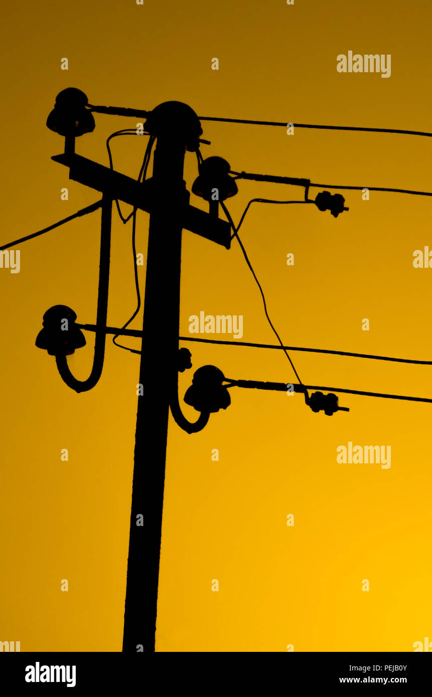 Antique Vintage conducteur électrique avec des fils et des isolants dans la nuit avec un ciel orange clair en arrière-plan, Subcarpathia région, la Pologne. Banque D'Images