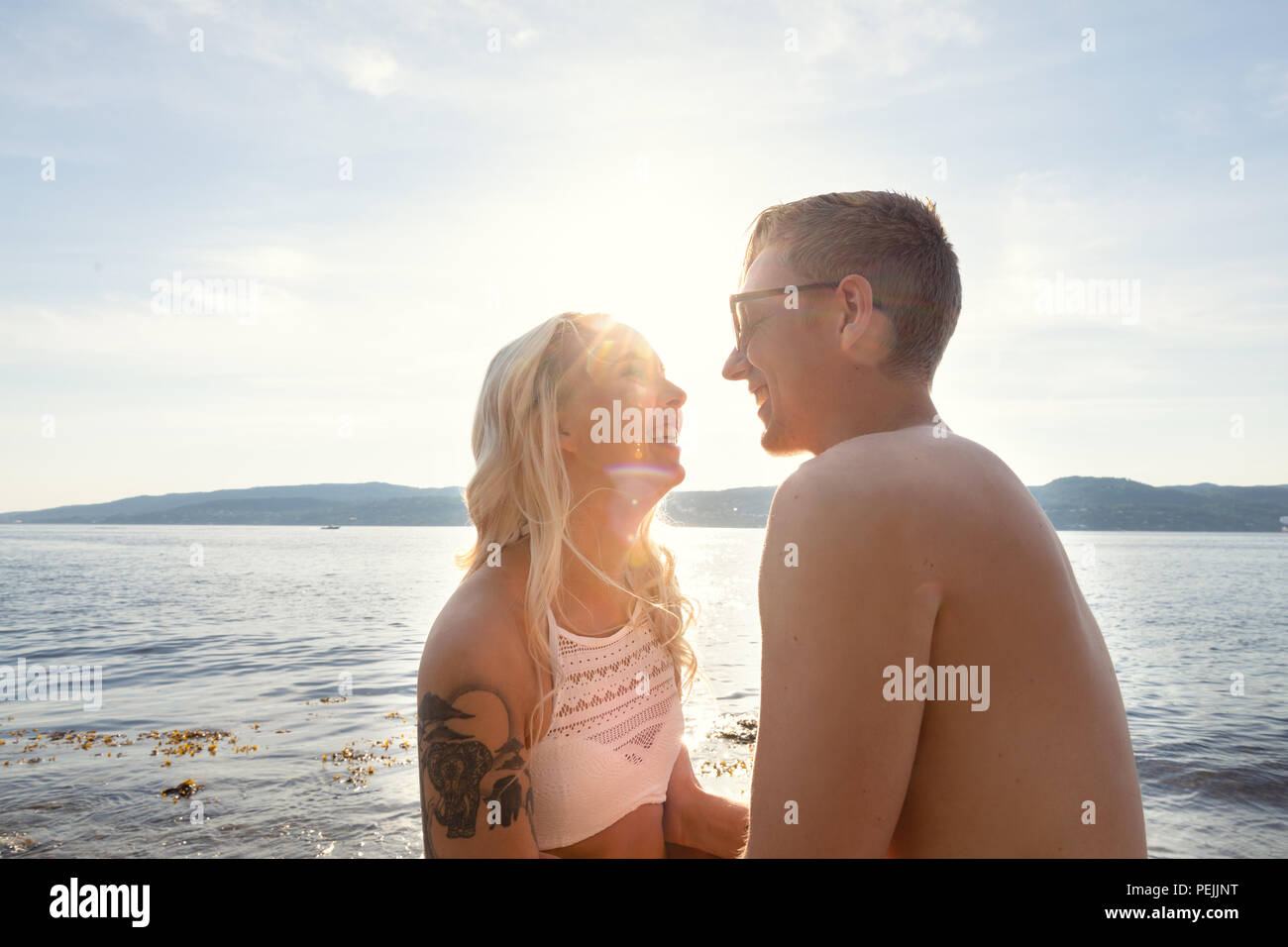 Laughing couple dans l'amour de rire de la plage contre sun Banque D'Images