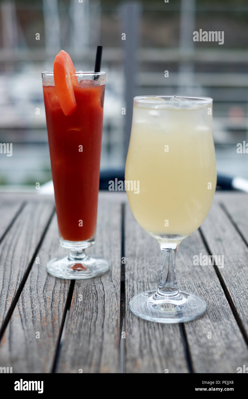 Deux verres, un Bloody Mary et un thé glacé au gingembre, à l'extérieur sur une table en bois Banque D'Images