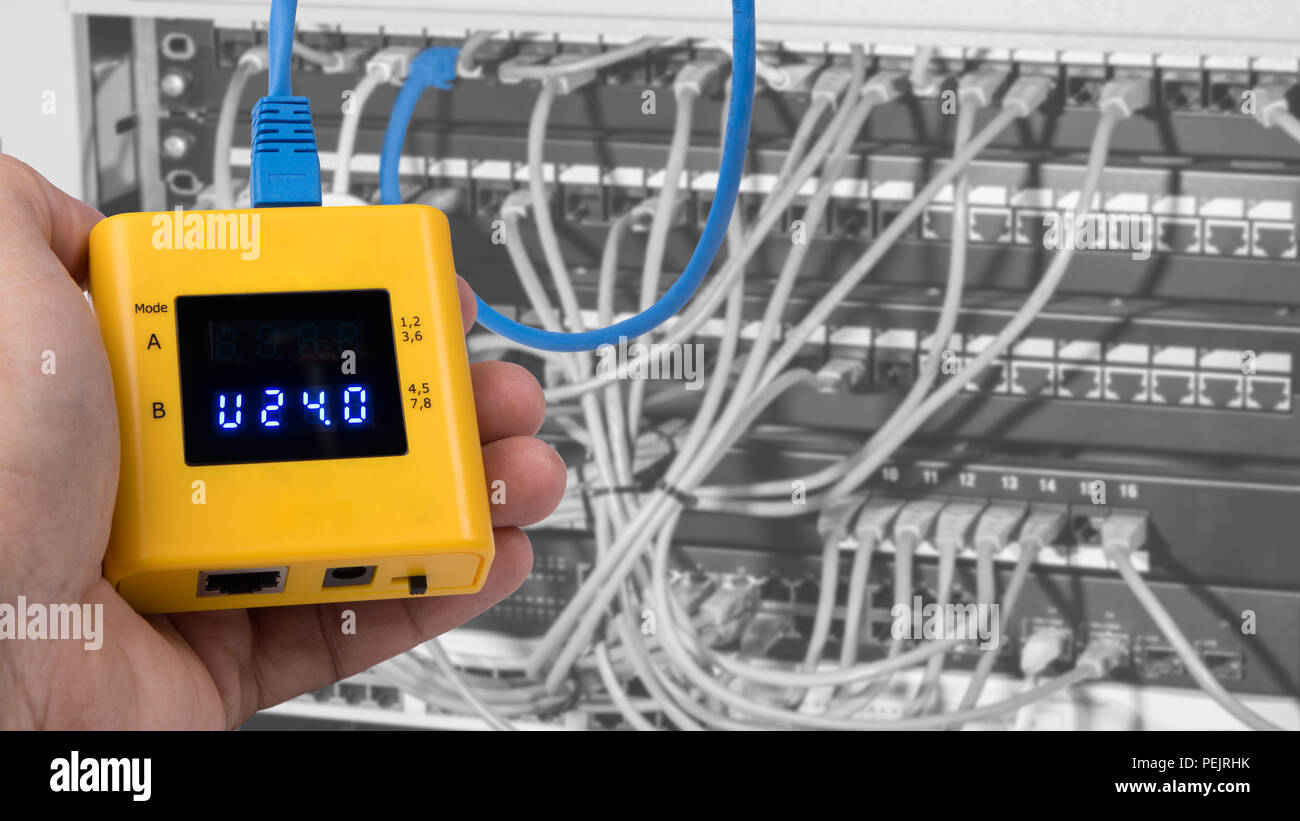 L'essai de la technologie PoE sur les câbles connectés dans les panneaux de rack case. Main humaine détail câblage structuré lors du calibrage de l'instrument de mesure par un carton jaune. Banque D'Images