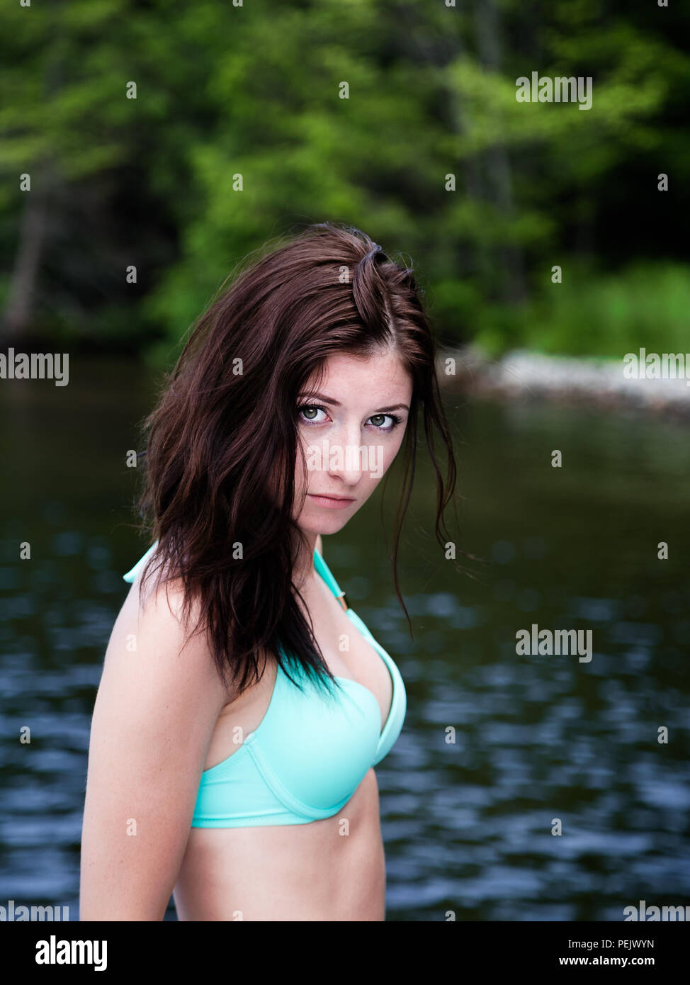 Portrait d'une jolie jeune femme posant devant un lac. Banque D'Images