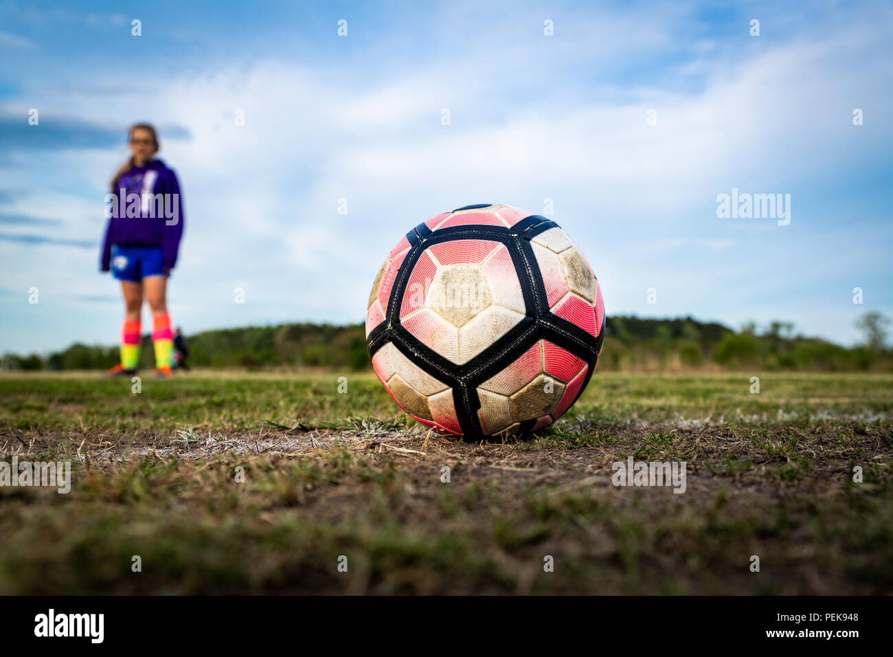 Une jeune fille se tient derrière un ballon de soccer, la préparation d'un coup de pied. Concepts : youth sports, athlète, l'accent, la préparation, la pratique, l'intensité, l'aspiration, Banque D'Images
