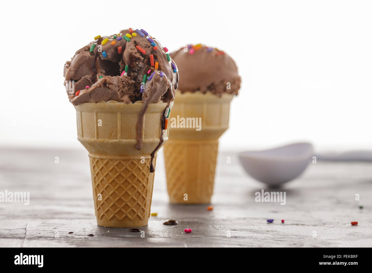 Un gros plan d'un cornet de crème glacée au chocolat avec le sirop de chocolat et de paillettes. Banque D'Images