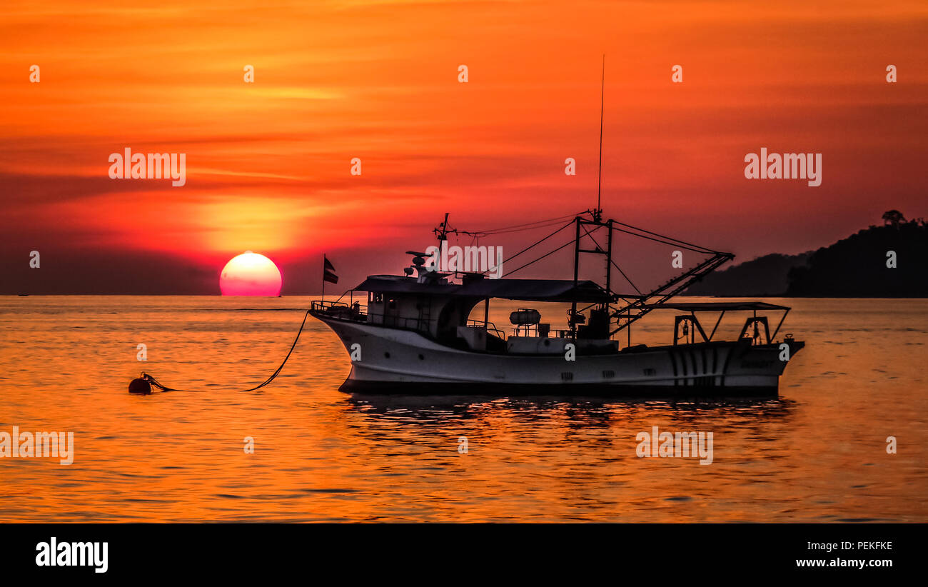 Vue paysage d'un coucher de soleil sur la mer de Chine du sud dans la région de Kota Kinabalu (Bornéo, Malaisie), avec un vieux bateau de pêche dans l'avant-plan Banque D'Images