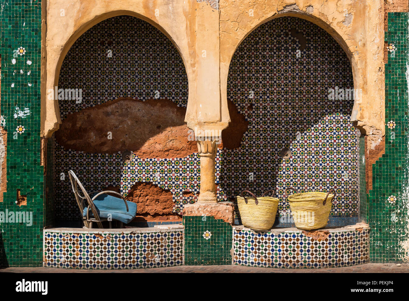 Robinet d'eau non fonctionnels sur la rue à Rabat, Maroc. Motif géométrique de la mosaïque colorés traditionnels. Deux paniers sur le petit mur et d'un o Banque D'Images