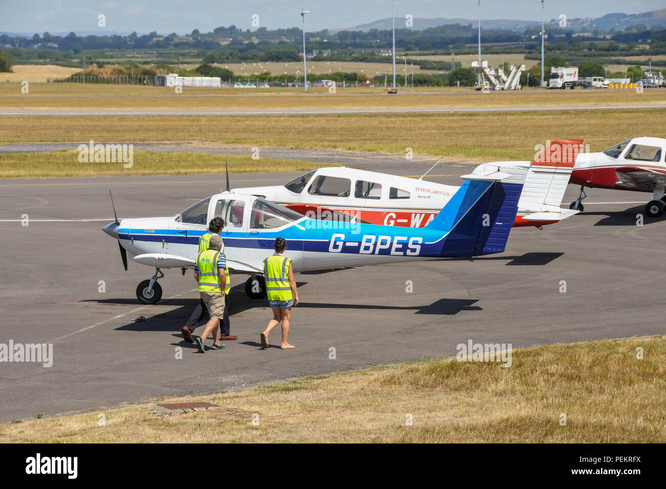 Les gens dans les gilets haute visibilité devant une rangée d'avions garés à l'aéroport de Cardiff au Pays de Galles. Banque D'Images