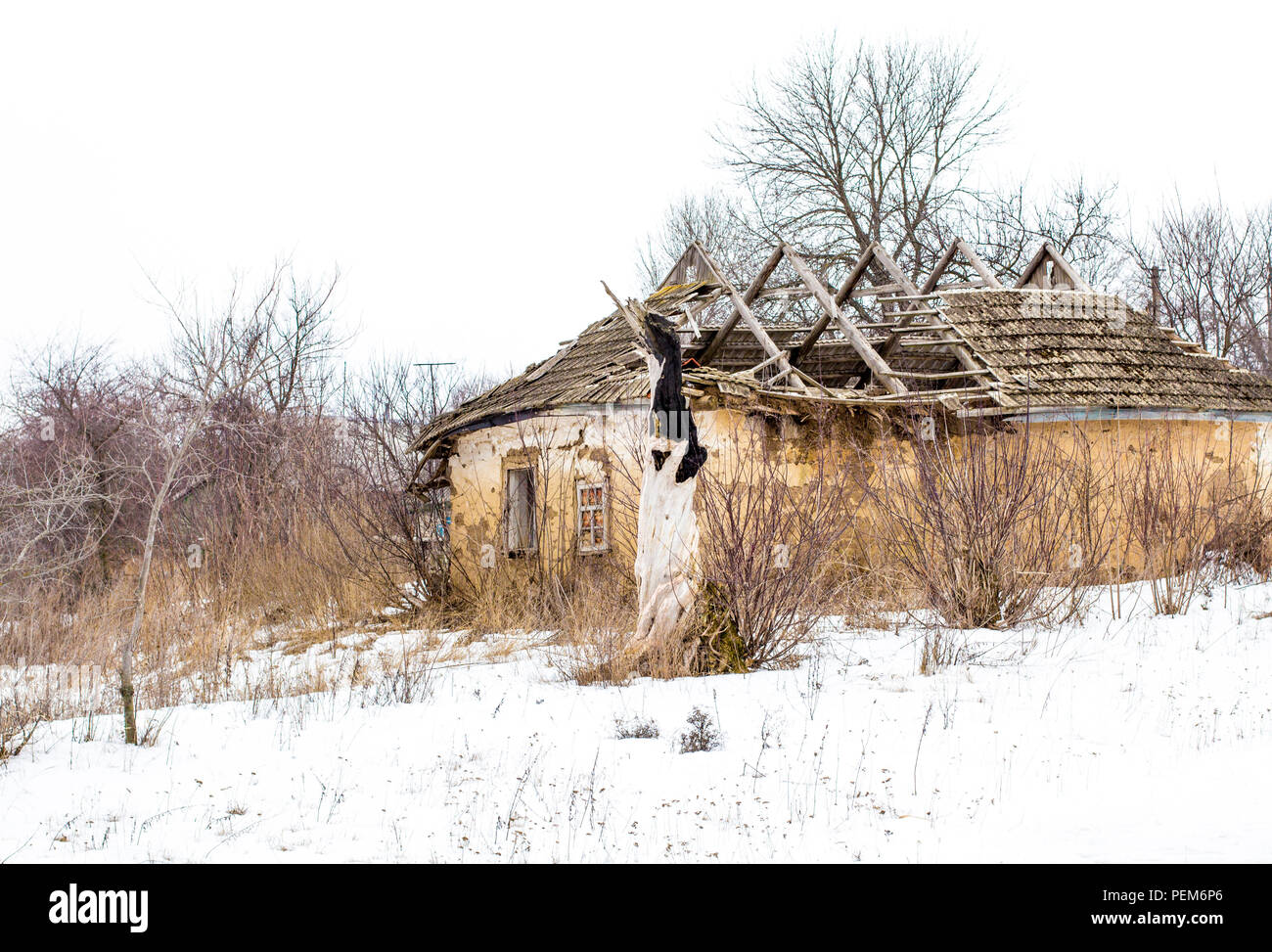 Ancienne maison d'argile dans le village ukrainien. Maison de l'argile en ruine dans la neige. Les ruines de la maison et de l'argile sèche des arbres. Banque D'Images