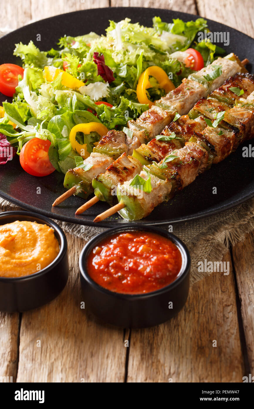 Rustique maison shish kebab en brochettes de légumes avec salade fraîche sur une plaque et les sauces close-up sur une table verticale. Banque D'Images