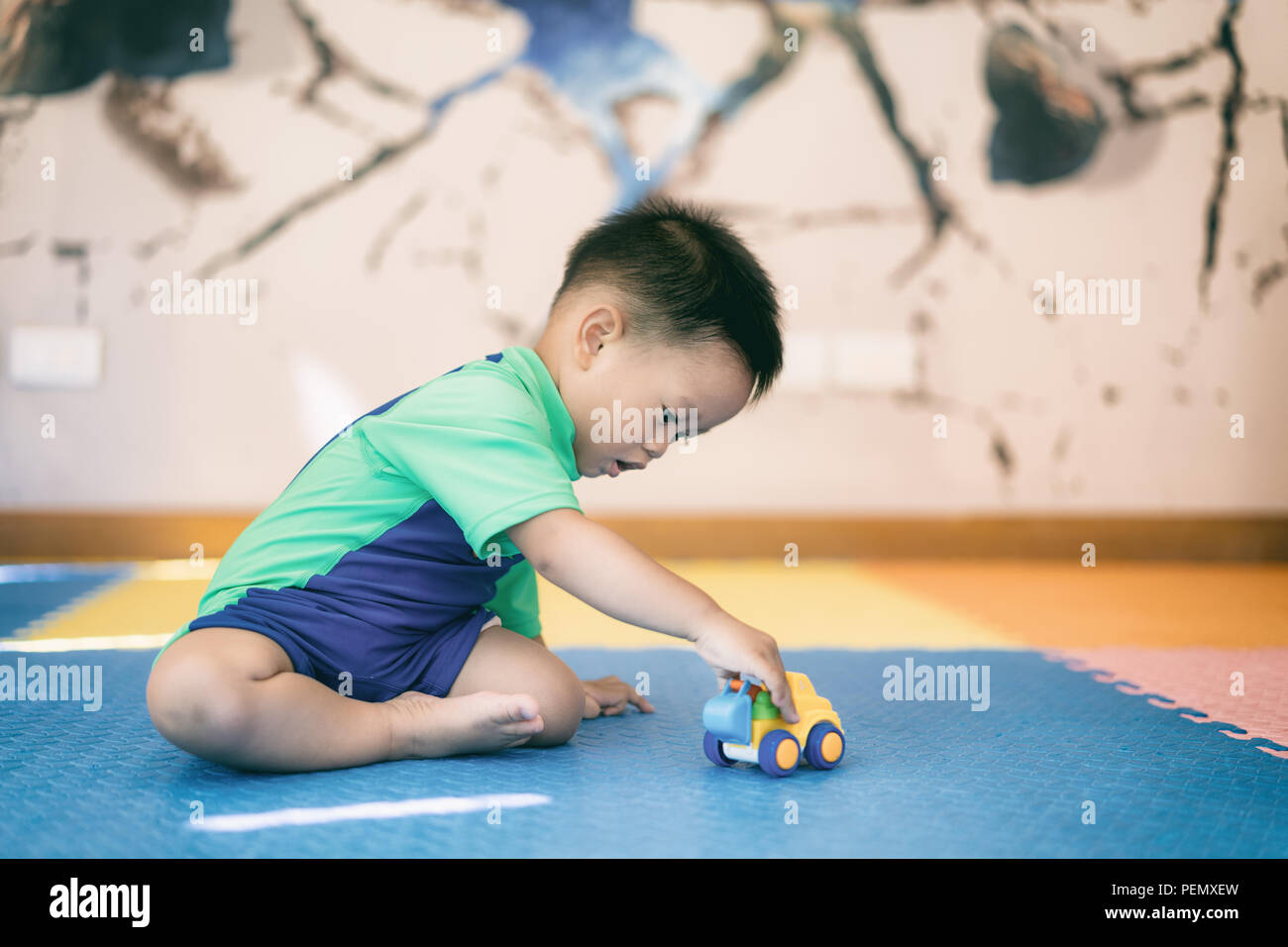 Asian kid toddler boy playing with toy car à l'intérieur la maison. Banque D'Images