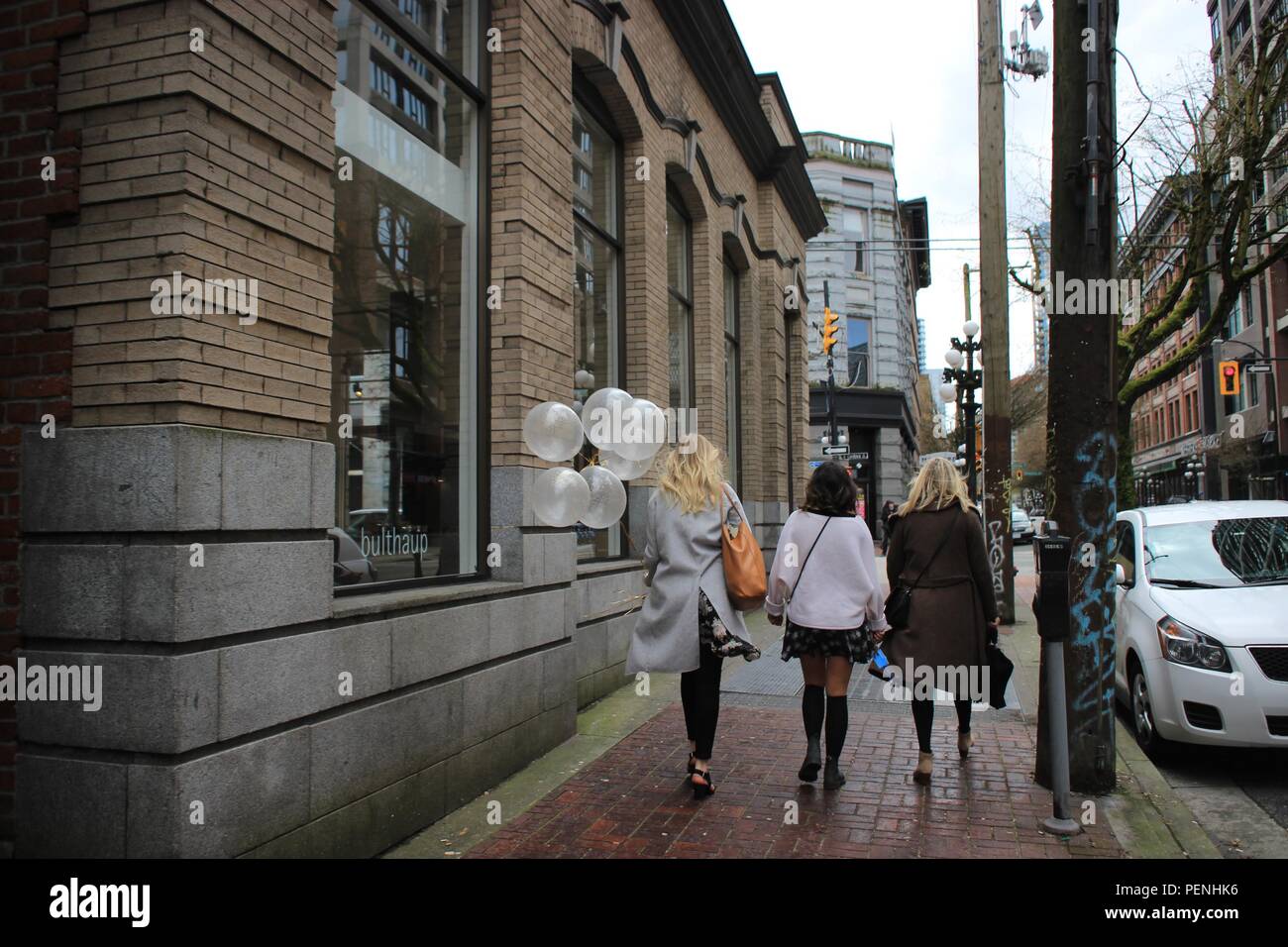 Trois femmes marchantes dans la rue avec des ballons blancs à Gas Town, Vancouver, Canada Banque D'Images