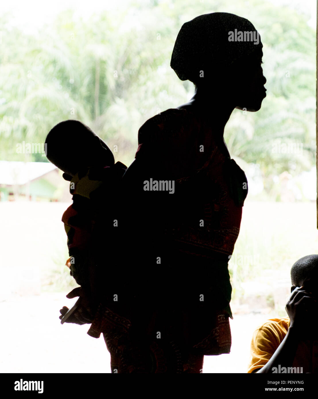 La silhouette d'une femme est titulaire d'un enfant à un service religieux à Ganta, au Libéria Banque D'Images