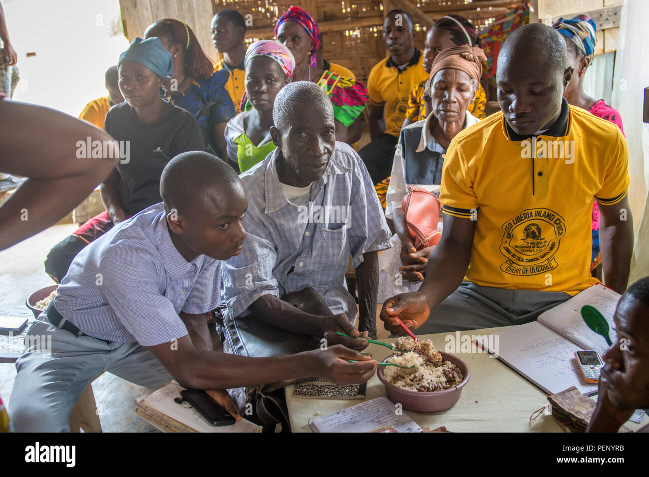 Trois hommes partagent un bol de riz et de ragoût dans Ganta, Libéria Banque D'Images