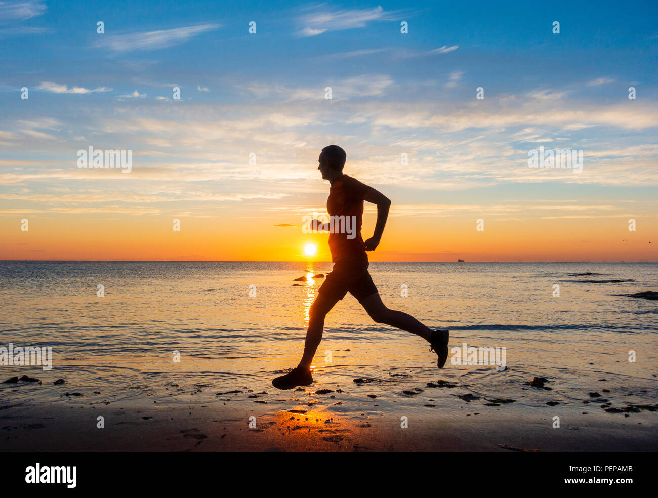 Seaton Carew, County Durham, Angleterre. United Kingdom. 17 août, 2018. Météo France : un matin tôt jogger sous un ciel magnifique au lever du soleil à Seaton Carew le vendredi. La queue de la tempête tropicale Ernesto devrait apporter de fortes pluies à de nombreuses régions du Royaume-Uni le dimanche. Credit : ALAN DAWSON/Alamy Live News Banque D'Images