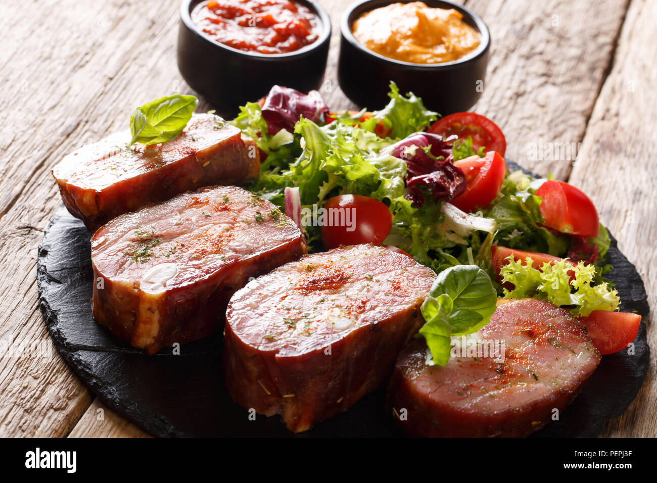 Côtes de porc fumé et salade de légumes frais sur une plaque en ardoise avec du ketchup et de la moutarde. Banque D'Images