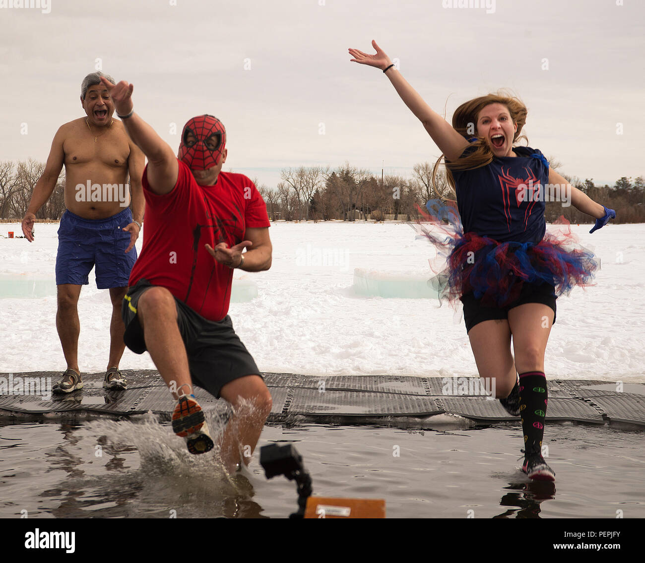 Gene Duran, 90e Escadron de génie civil, et Racheal Comisky, 90e Escadron de soutien de la Force, du Centre de développement de l'enfant sauter dans les eaux glacées de l'Cheyenne Sloan Lake le 16 janvier 2016. Gil Ferrel, 90e CES, hésita avant de braver le froid du Wyoming pour une courte trempette au cours de la quatrième année de Matthew S. Schwartz Polar Memorial plongent. (U.S. Photo de l'Armée de l'air par R.J. Oriez) Banque D'Images