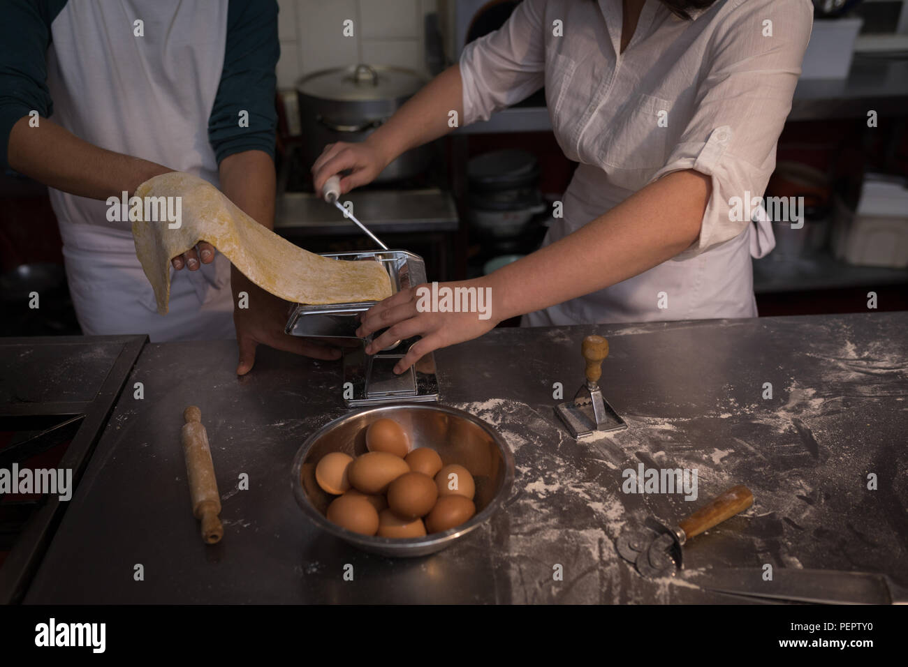 Les boulangers de l'utilisation de la machine pour la préparation de pâtes dans une boulangerie Banque D'Images