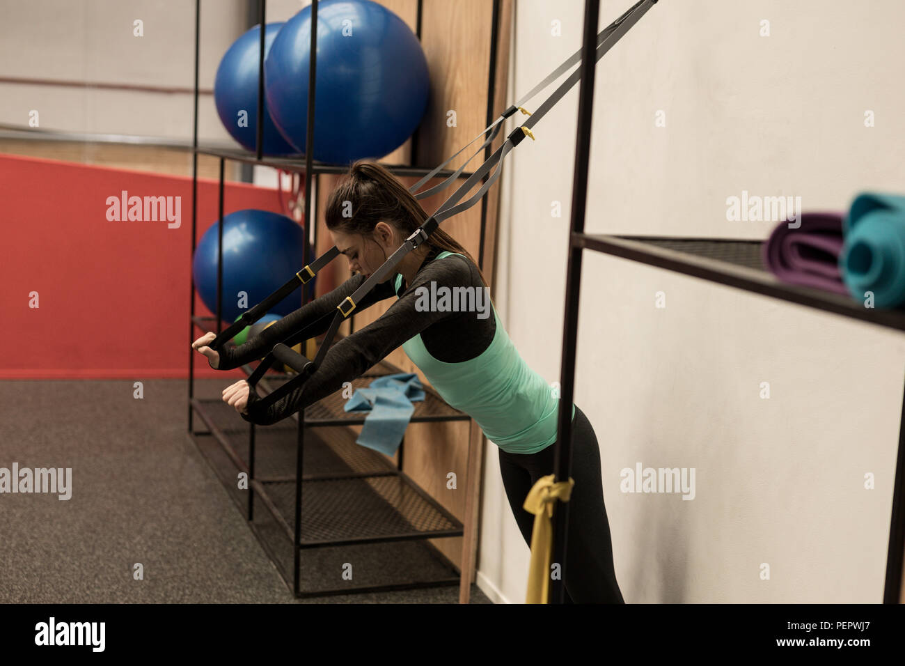 Woman doing exercise avec câble de suspension in fitness studio Banque D'Images