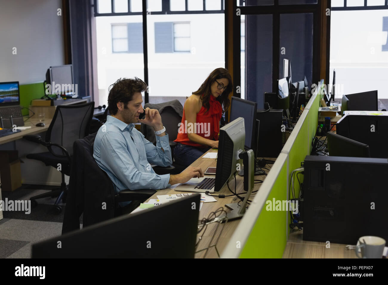 Businessman talking on mobile phone while using laptop Banque D'Images