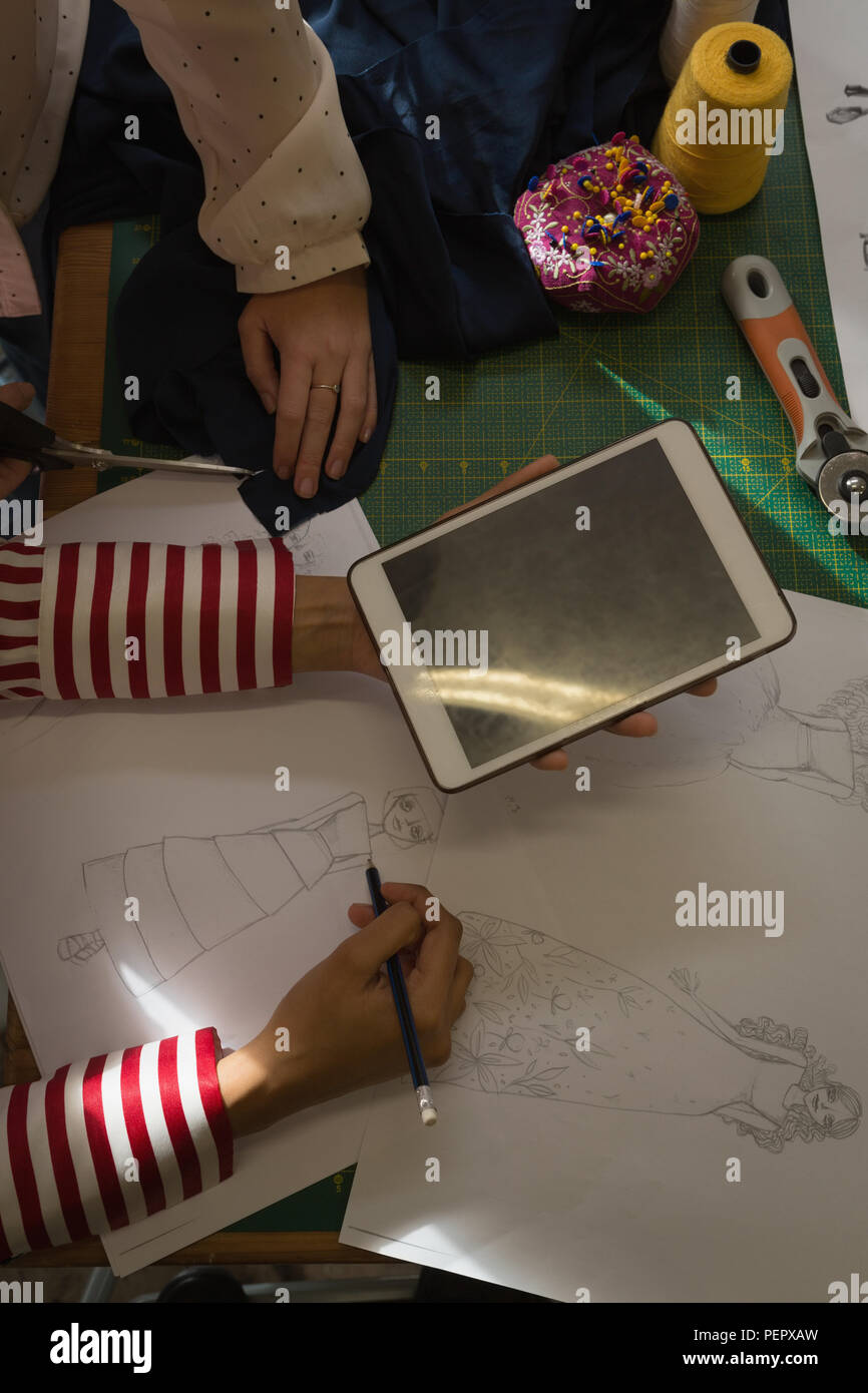 Les créateurs de mode dessiner un croquis using digital tablet in fashion studio Banque D'Images