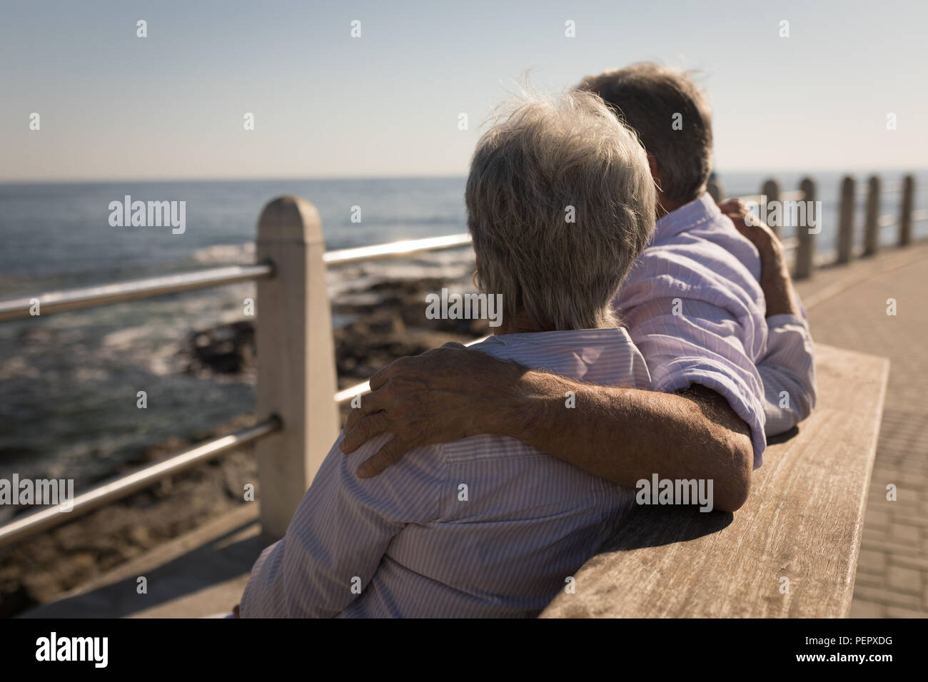 Senior couple sitting on bench avec bras autour de Banque D'Images