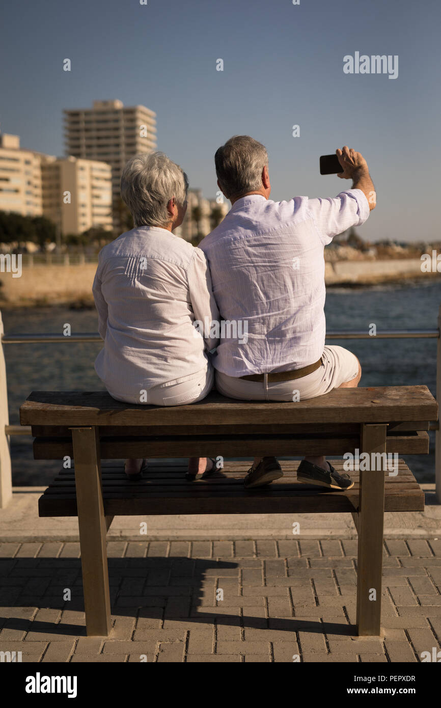 Tout en selfies woman sitting on bench à la promenade Banque D'Images
