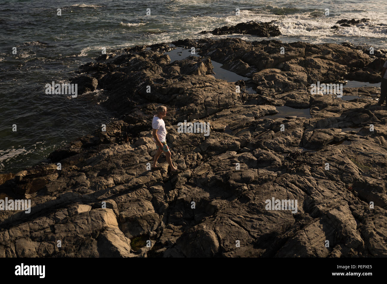 Man Walking on rock at beach Banque D'Images Man Walking on rock at beach Banque D'Images