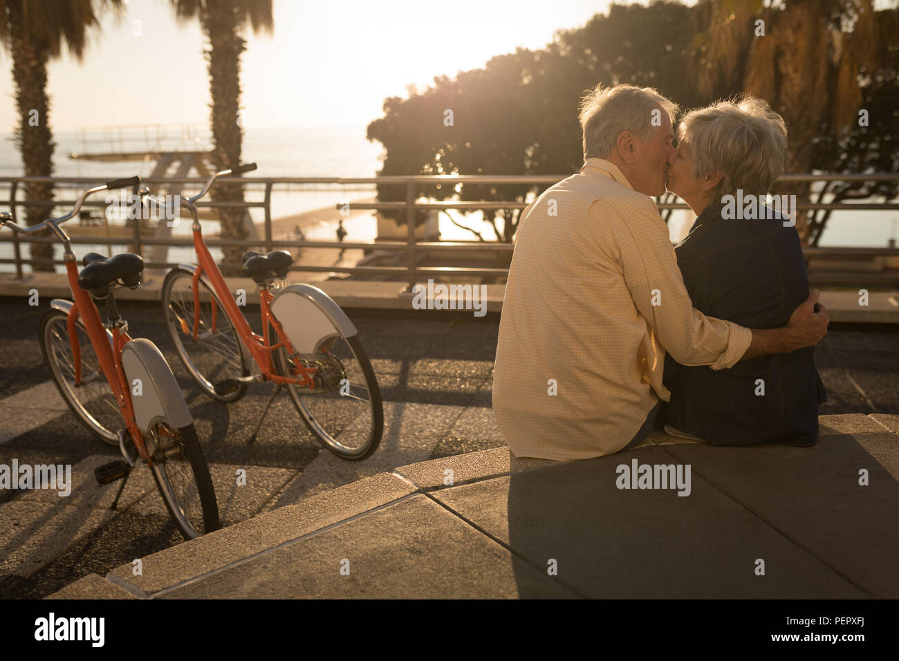 Senior couple kissing on mur siège à la promenade Banque D'Images