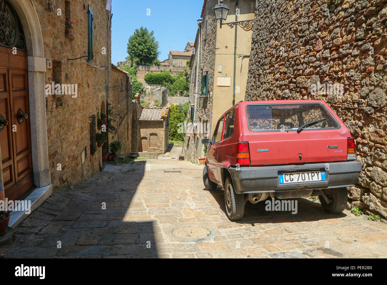 Une photo de l'ancien italien ville toscane Volterra. La vieille voiture est debout dans la rue solitaire de maisons en pierre. Banque D'Images