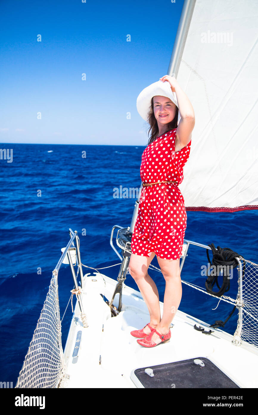 Femelle sur voilier. Une jeune femme en robe rouge et chaussures rouges et  un chapeau sur un yacht dans le contexte de la voile et de la mer Photo  Stock - Alamy
