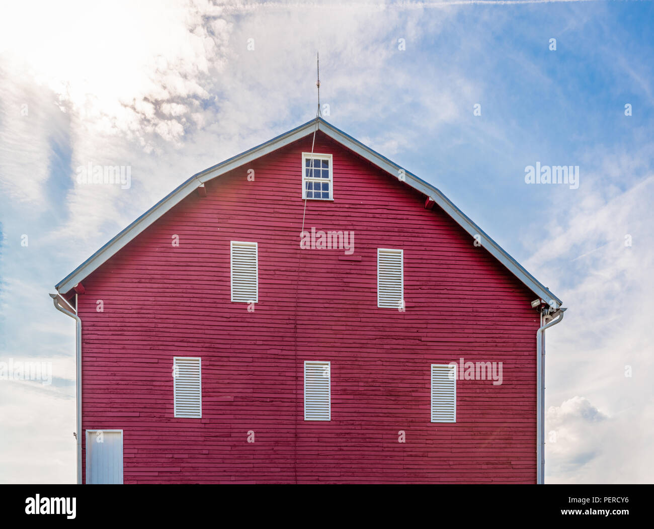 Une grange rouge vif sur les terres agricoles de l'Ouest Virginie sous un soleil éclatant dans un ciel d'été bleu partiellement nuageux Banque D'Images