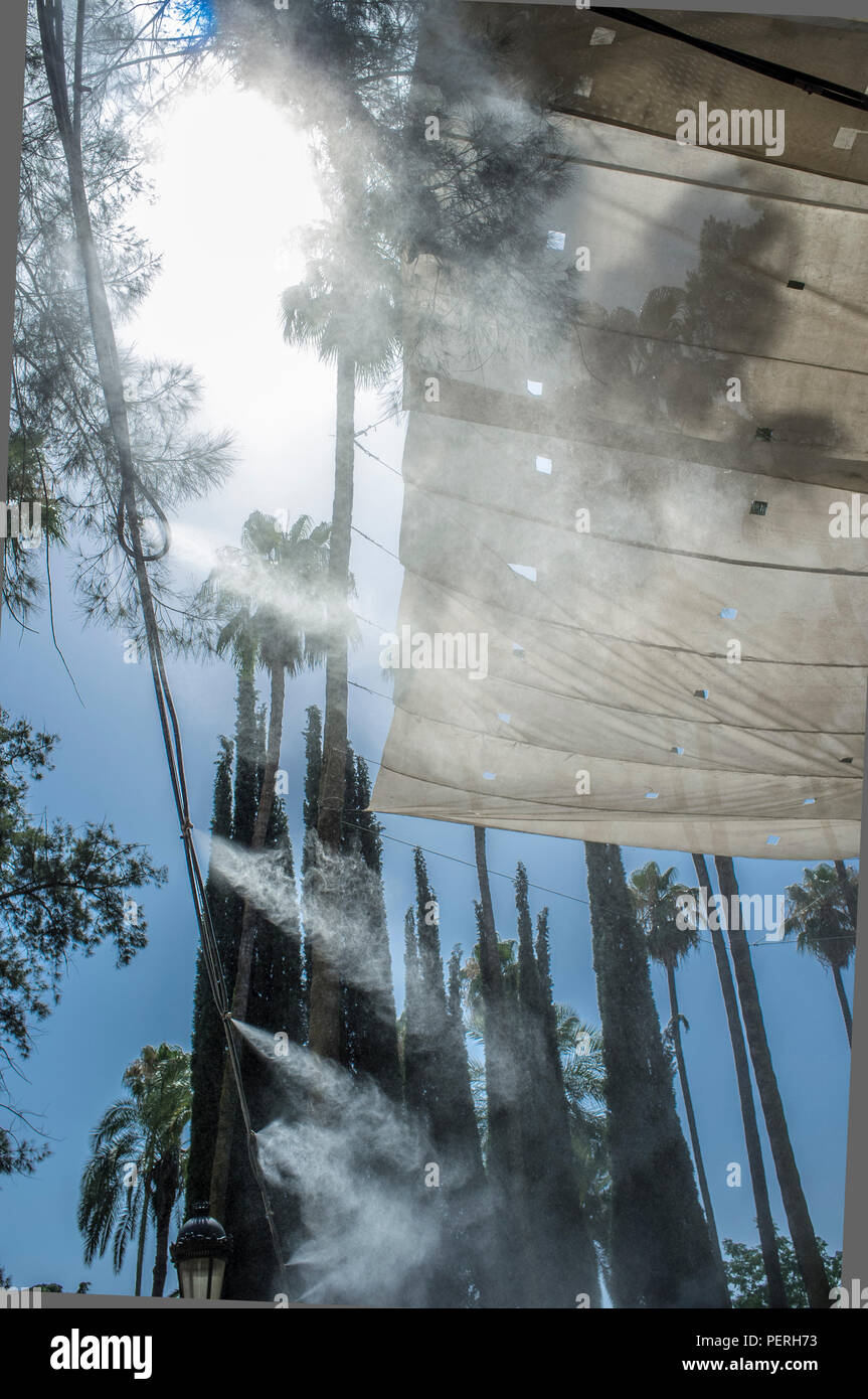 Têtes d'auvents et éclaboussures d'eau vaporisée au parc public. Dispositifs pour le refroidissement de la température de l'été en Espagne à l'extérieur Banque D'Images